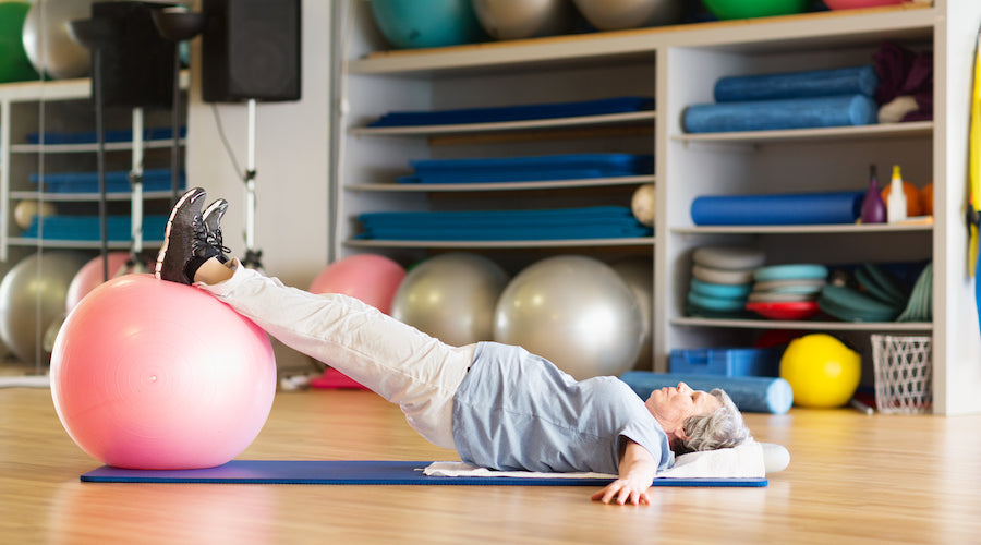 Elderly lady exercise on mat with a large ball